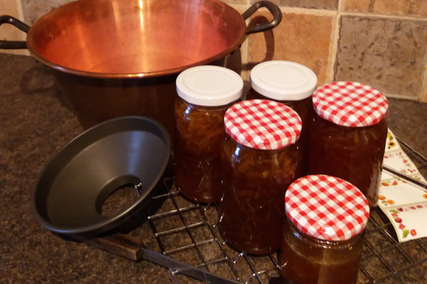 Picture of jars of marmalade on a worktop with copper preserving pan